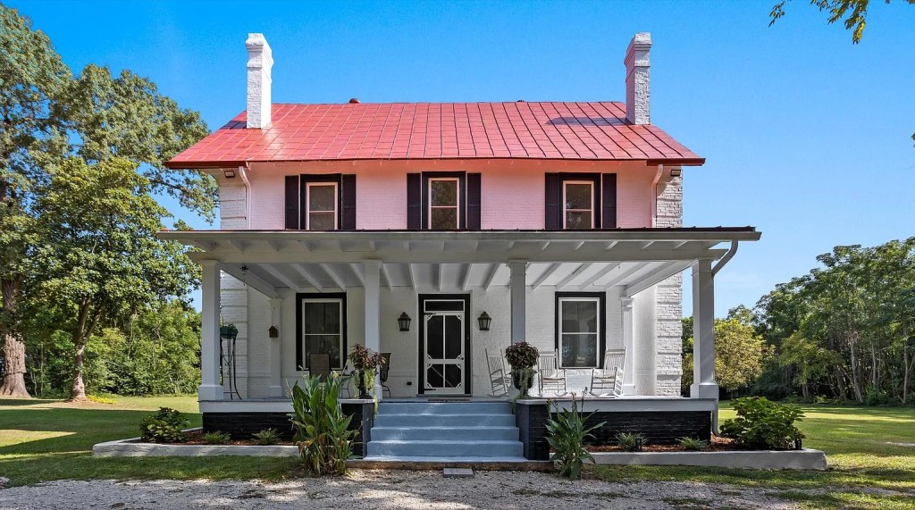 Restored 1925 white Farmhouse in South Carolina with big front porch and red roof. 