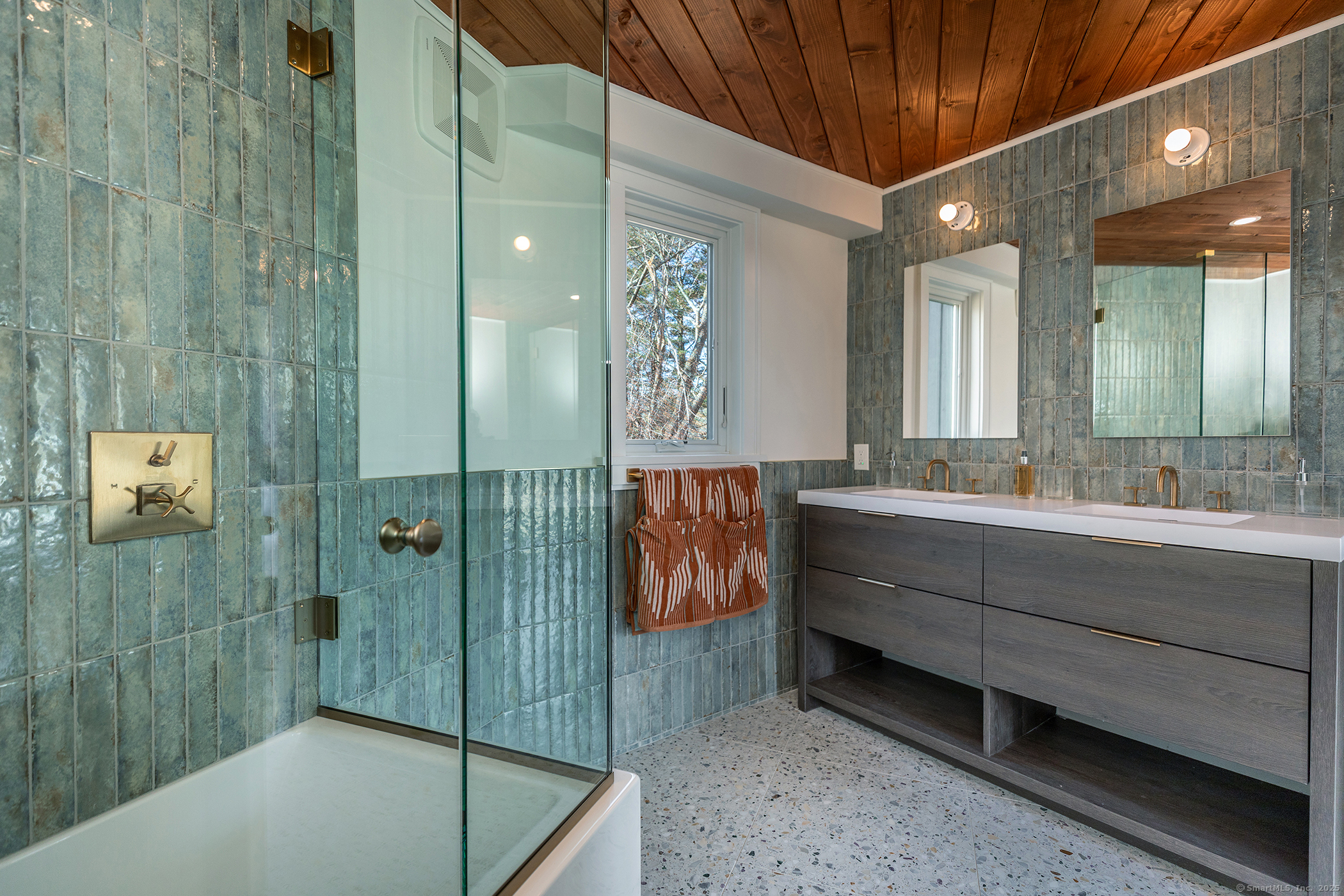 Teal tile bathroom with sleek fixtures and natural light.
