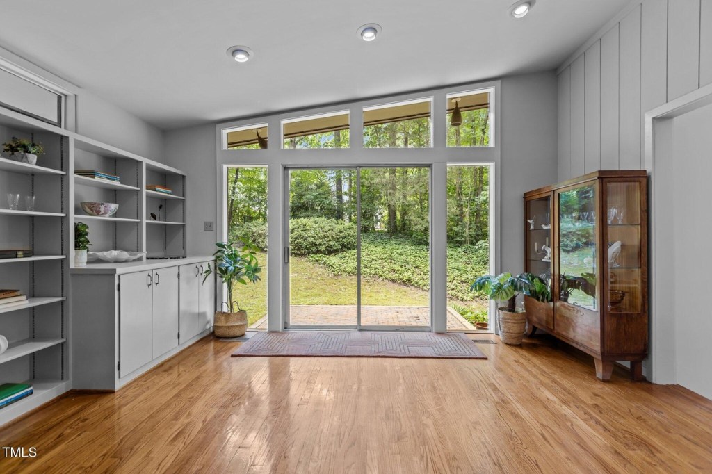 Light-filled mid-century modern living room with clerestory windows, sliding glass doors, and built in bookshelves.
