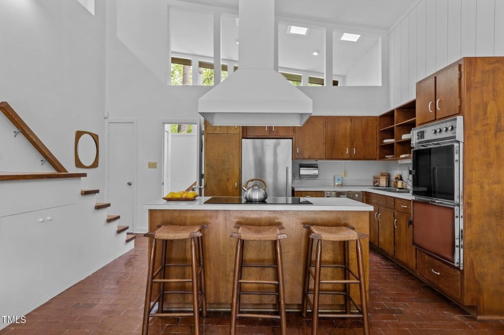 Open-concept mid-century kitchen area with wood accents and clerestory windows.
