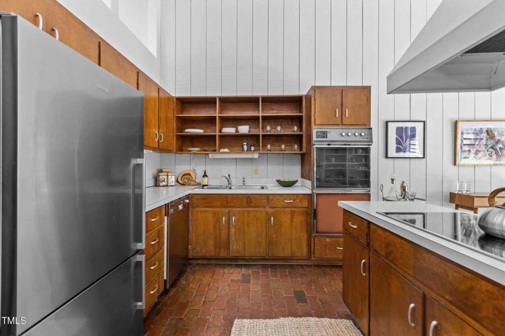 Open-concept mid-century kitchen area with wood accents and clerestory windows and brick floors.
