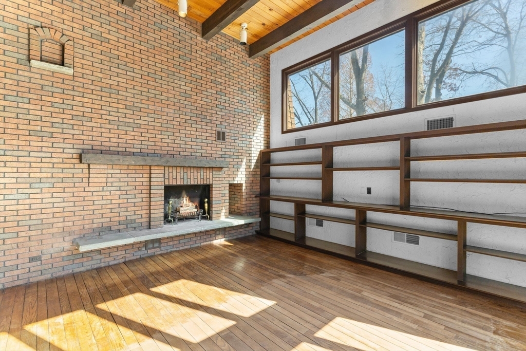 Living room with brick wall with fire place and built in bookshelves and clerestory windows. A mid century modern home in Massachusetts.