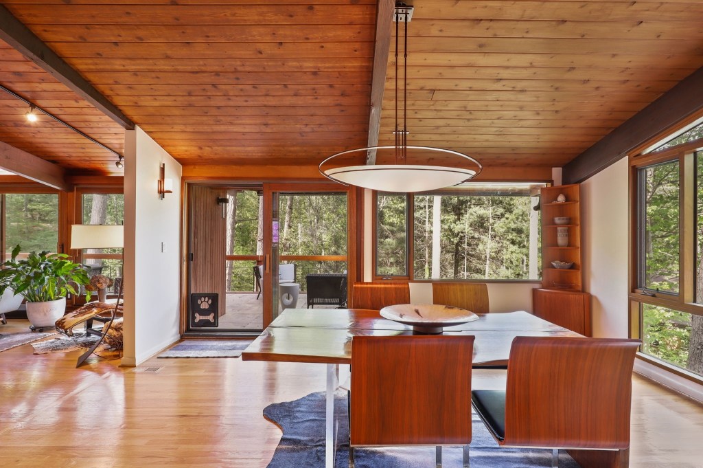 Open-plan dining space with retro decor, modern lighting and forest-facing windows.
