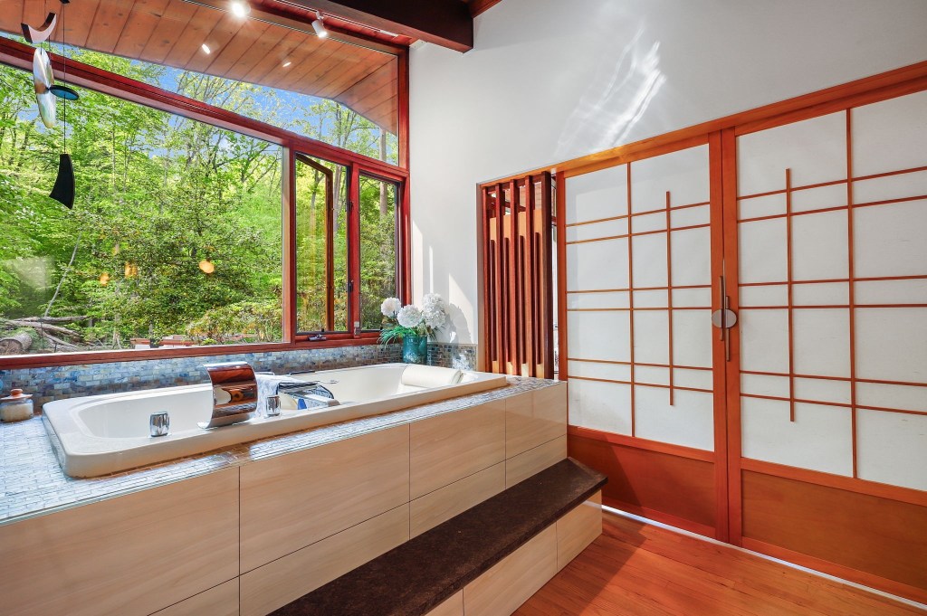 Vintage mid-century bathroom with spa bath and wood ceiling and big bright open windows with garden view
