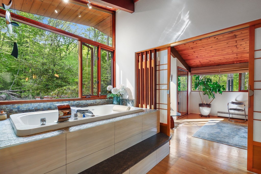 Vintage mid-century bathroom with spa bath and wood ceiling and big bright open windows with garden view and sliding doors
