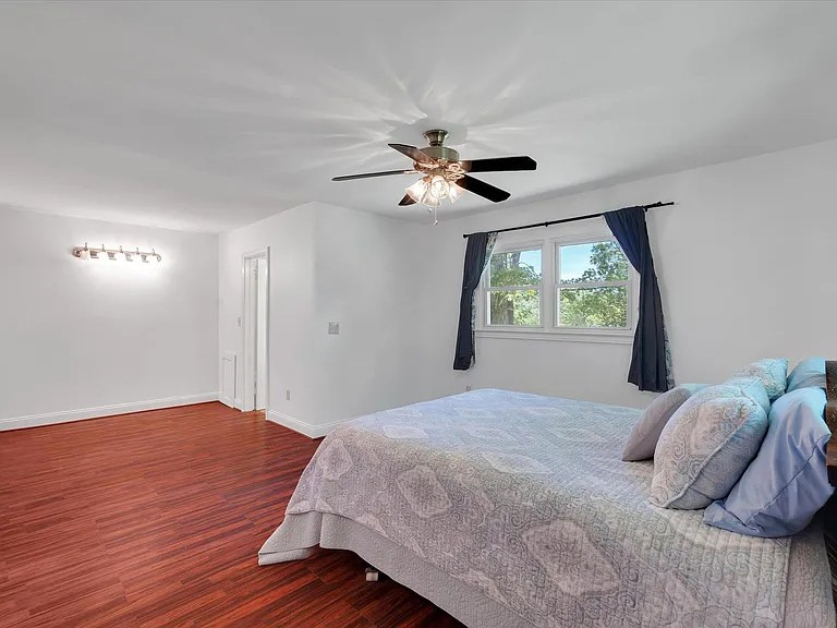 Large primary bedroom with ample windows and tranquil wooded views

