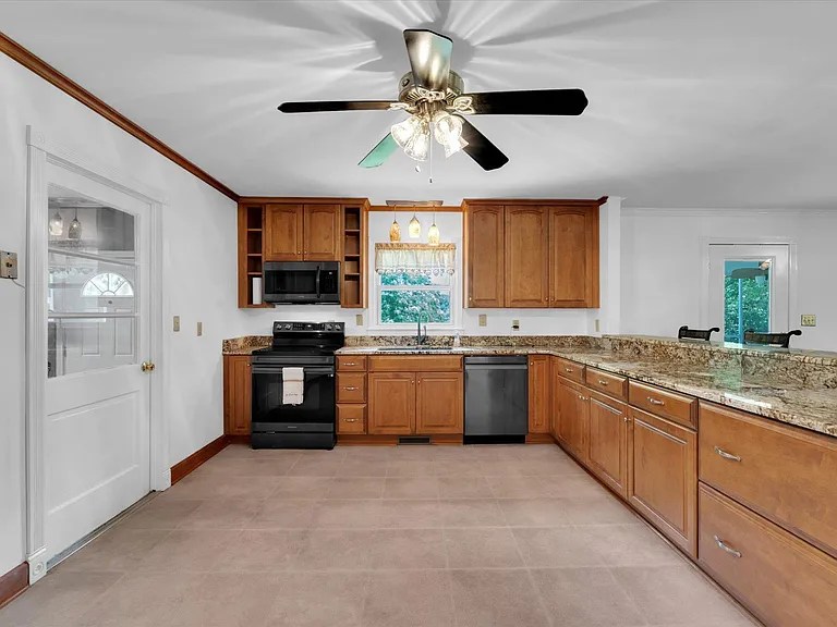 Charming country-style kitchen with wood cabinetry and black appliances

