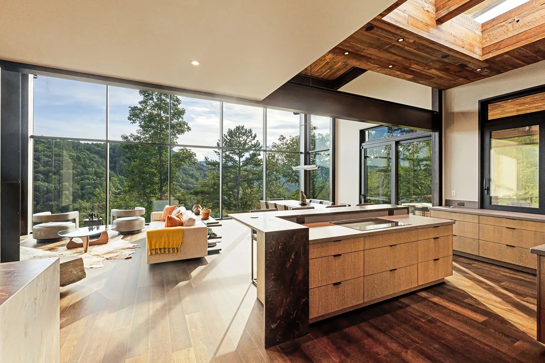 Open-concept living room with natural finishes and floor-to-ceiling windows overlooking nature

