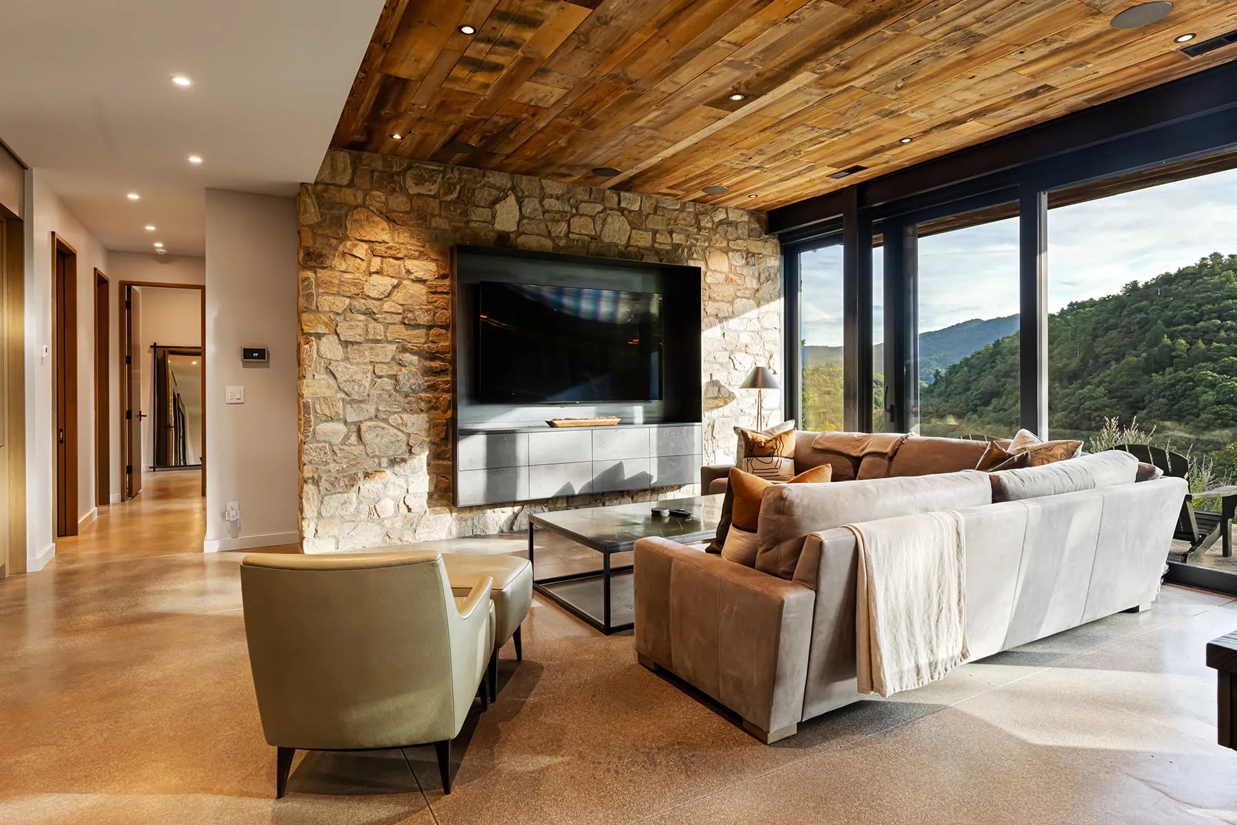 Open-concept living room with natural finishes and floor-to-ceiling windows overlooking nature

