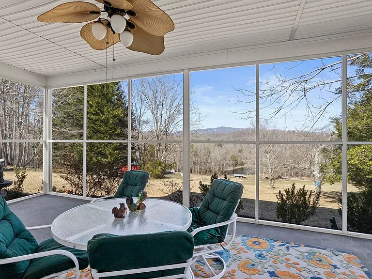 Spacious back screened-in porch overlooking mature trees and distant mountains, ideal for relaxing
