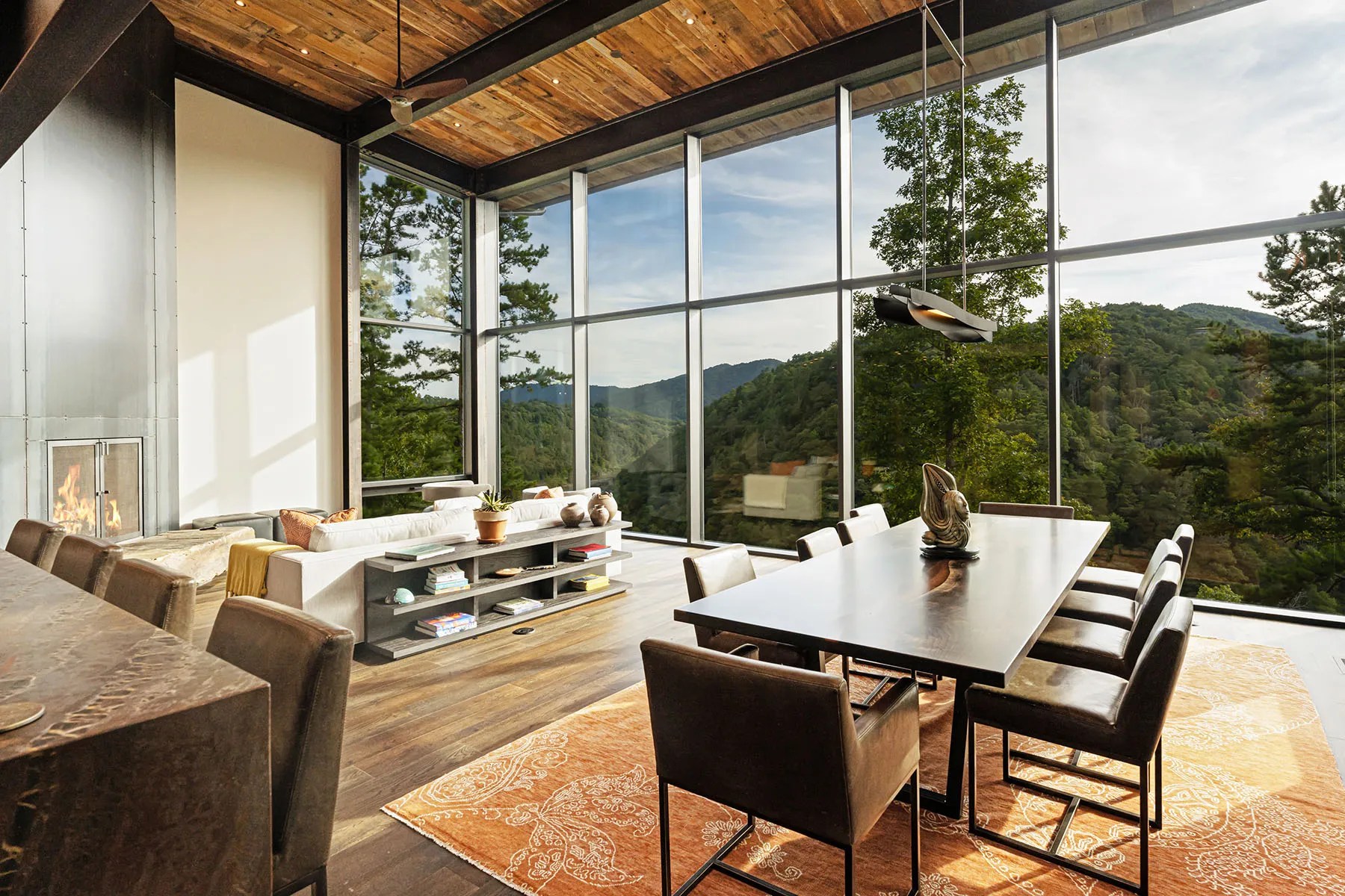 Open-concept living room with natural finishes and floor-to-ceiling windows overlooking nature

